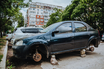 A car without wheels parked on the street. Thieves substituted stones for wheels. Vandalism