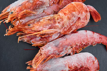 Frozen seafood. Fresh shrimps on dark background. Red raw prawns