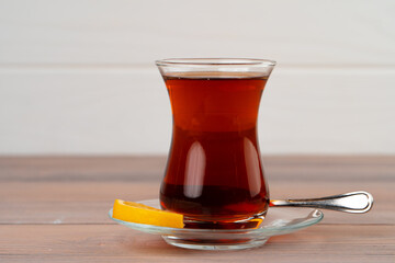 Turkish tea in glass cup with piece of lemon on wooden table