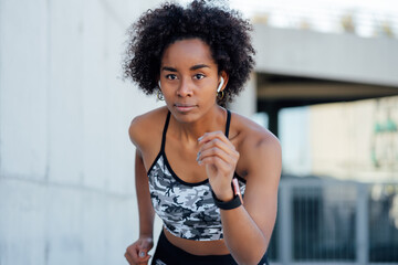 Naklejka na ściany i meble Afro athletic woman running outdoors.