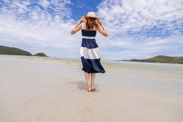 Woman barefoot walking on summer along wave of sea water and sand on the beach.