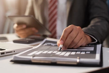 Businessman using a tablet to analysis graph company financial at office in the morning.