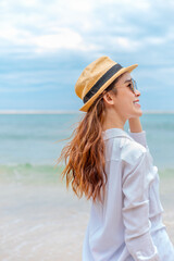 Fototapeta na wymiar smiling young woman in sun hat and waring sun glasses on the beach. summer, holidays, vacation, travel concept