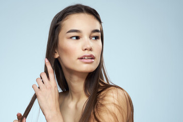 Pretty brunette with bared shoulders long hair body care blue background