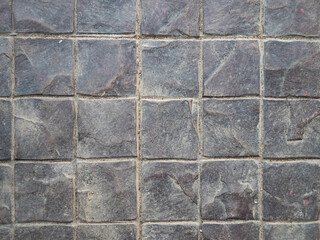 Concrete paving stone texture. Covering the sidewalk. Square tiles. Sand and dirt in the joints between tiles.