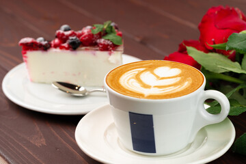 Cup of latte coffee with piece of berry cheesecake