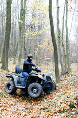 Fototapeta na wymiar Travel without roads. ATV. A man rides through the forest on an all-terrain vehicle. Quad bike. In the woods. ATV trip to the forest
