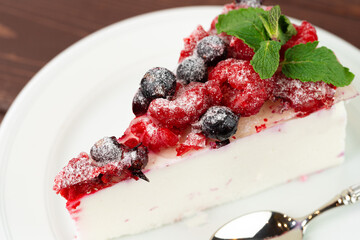 Piece of berry cheesecake served on brown wooden table