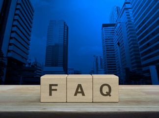 FAQ word on block cubes on wooden table over modern office city tower and skyscraper, Frequently asked questions, Business customer service and support concept