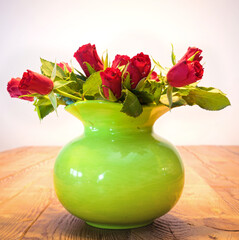 red roses in a vase on a table from old boards 