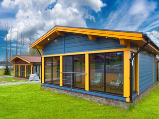 Two cottages on the lake. Houses with panoramic Windows and a place to relax. Autumn vacation in cottages. Country houses on the background of nature.