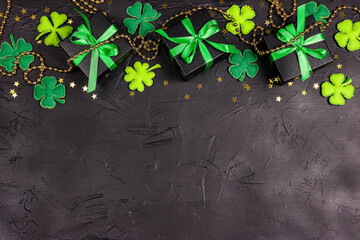 Saint Patrick's Day concept. Border of decorative clover leaves, gift boxes and gold stars on black...