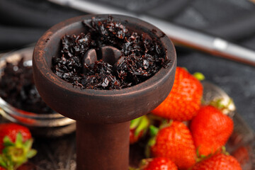 Hookah parts and strawberry on gray surface close up
