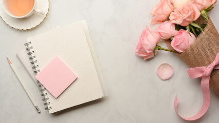 Stationery on marble table with roses brunch and coffee cup in home office room