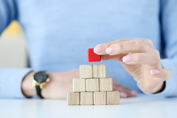 Woman building pyramid from wooden cubes closeup