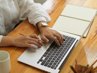 Female hands typing on laptop keyboard on study table with stationery