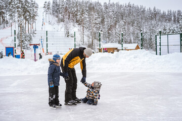 young caucasian bearded man teach boys how to skate. Father's day concept. cute caucasian boys...