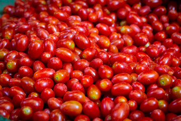 Pile of tomatoes for sale at market. Background image on the subject of organic, vegan or vegetarian raw food.