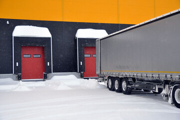 Delivery of goods by truck to a warehouse complex in winter.