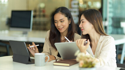 Two businesswomen consulting on their work while meeting in office room