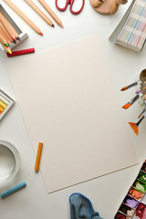 Artist workspace with mock up paper and paint tools on white table