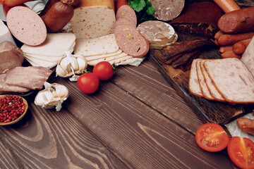 Assortment of different sausages laid out on brown wooden background