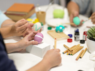 Hands painting easter eggs, preparing for easter festival with painting tools