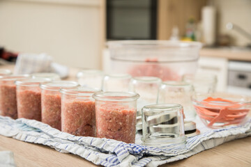 Frau füllt Hackfleisch aus Schwein und Rind roh in Einkochglas und Weckglas zum Einkochen Einwecken selbdstgemacht in Küche für Haltbarkeit und Vorrat