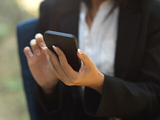 Businesswoman texting message on smartphone while relaxing at outdoor