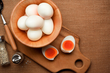 A lot of boiled eggs in wooden bowl and half sliced boiled egg on the kitchen table