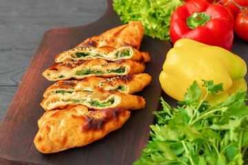 Stuffed bread, turkish pie with herbs on wooden board