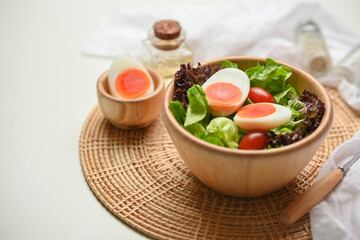 A bowl of of salad with boiled eggs, lettuce and tomato on wicker placemat
