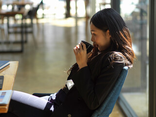 Businesswoman relaxing with coffee while sitting at workspace