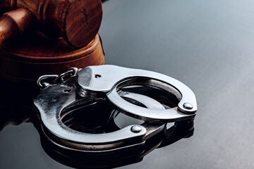 Judge mallet and handcuffs on black background