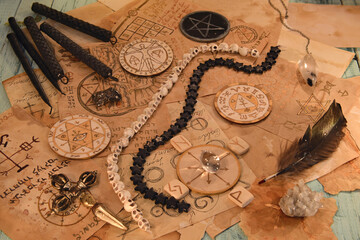 Old papers with magic spells and mystic ritual objects on witch table.