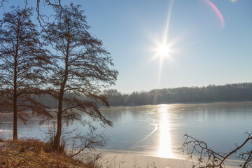 Aufgehende Sonne im Gegenlicht an der zugefrorenen Grube Fernie in Großen-Linden bei Gießen,...
