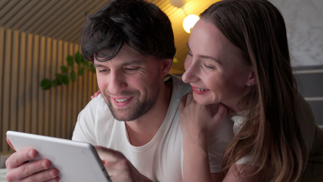 Young couple using tablet on bed in bedroom late at night