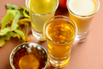 Fresh organic apple cider with apples and cinnamon over patel brown background. Close up three glasses.