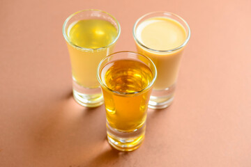 Fresh organic apple cider with apples and cinnamon over patel brown background. Close up three glasses.