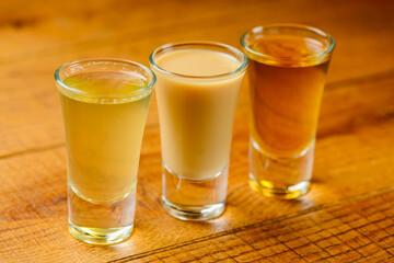 Fresh organic apple cider with apples and cinnamon over rustic wooden background. Close up three glasses.