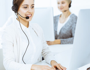 Call center. Group of diverse operators at work. Beautiful woman in headset communicating with customers of telemarketing service. Business concept