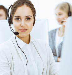 Call center. Group of diverse operators at work. Beautiful woman in headset communicating with...
