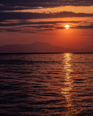 Obraz premium orange fiery sundown sky with some clouds over the calm sea, nature background