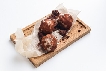 Chocolate potato dessert served on a rustic wooden board over white background.