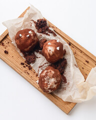 Chocolate potato dessert served on a rustic wooden board over white background.