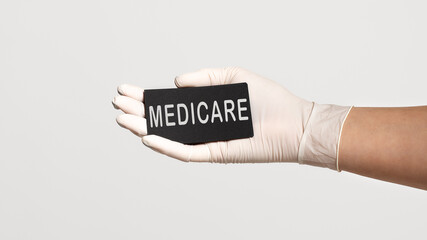 Closeup of the hand in a white sterile glove holding a card with word - MEDICARE