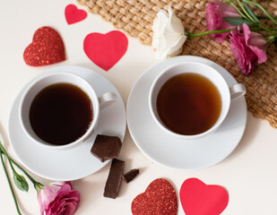 Magic mood atmosphere of love picture for post in Instagram. Two cup of tea or coffee with chocolate and flowers on white table with brown napkin. Free minute at work and enjoyment from rest. Close-up
