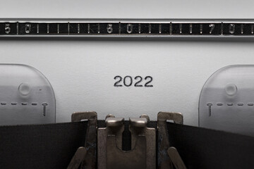 Typing text or numeral 2022 on vintage manual typewriter. Close up of writes year number on white...
