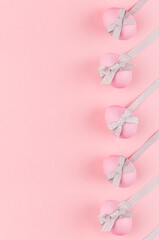 Pink easter eggs with grey bows and ribbons as border on pastel pink background, vertical, story.