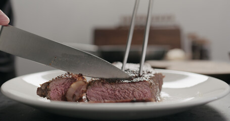 man slicing new york steak on white plate